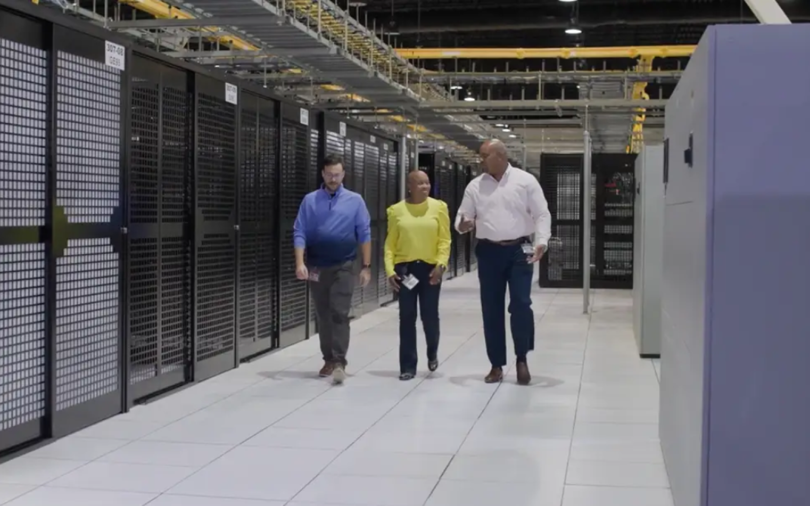 Three QTS employees walk down the hallway of a data center. Blackstone